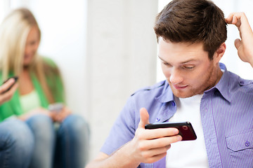 Image showing student looking at phone and writing something