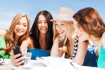 Image showing girls looking at smartphone in cafe on the beach