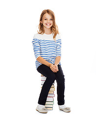 Image showing little student girl sitting on stack of books