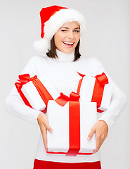 Image showing winking woman in santa hat with many gift boxes