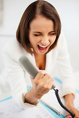 Image showing woman shouting into phone in office