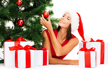 Image showing smiling woman in santa helper hat with gift boxes