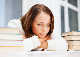 Image showing bored young woman with many books indoors