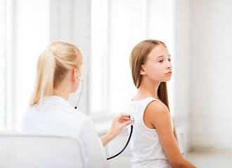 Image showing doctor with stethoscope listening to the patient