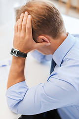 Image showing stressed businessman with papers at work