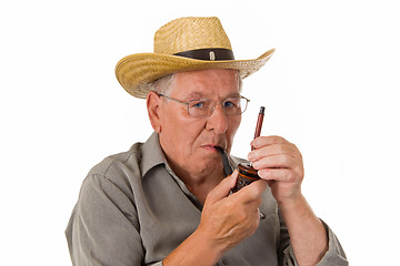 Image showing Old man lighting up a pipe