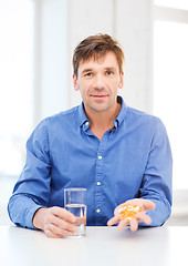 Image showing man at home showing lot of pills