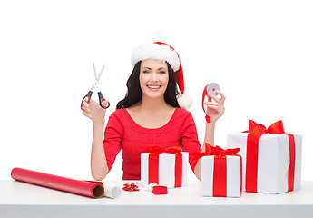 Image showing woman in santa helper hat with many gift boxes