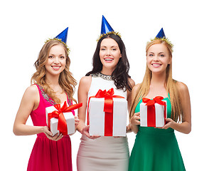 Image showing three smiling women in blue hats with gift boxes