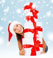 Image showing smiling woman in santa helper hat with gift boxes