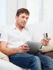 Image showing man with tablet pc and credit card at home