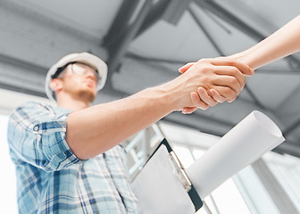 Image showing builder with blueprint shaking partner hand