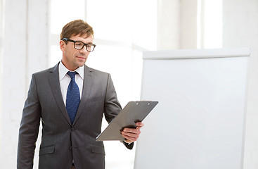 Image showing businessman pointing to flip board in office