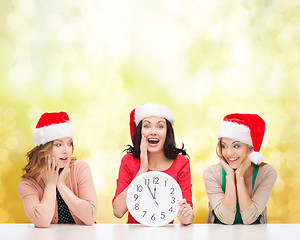 Image showing women in santa helper hats with clock showing 12