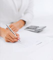 Image showing businesswoman working with calculator in office