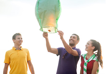 Image showing friends with chinese sky lanterns on the beach