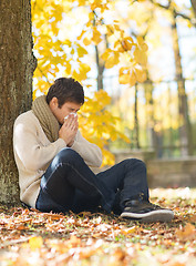 Image showing ill man with paper tissue in autumn park