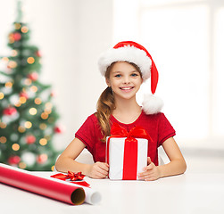 Image showing smiling girl in santa helper hat with gift box