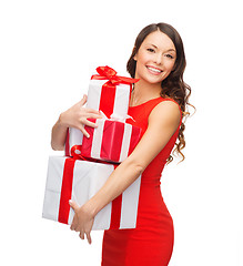 Image showing smiling woman in red dress with many gift boxes