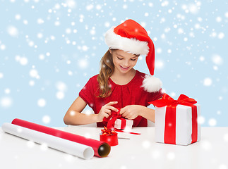 Image showing smiling girl in santa helper hat with gift box