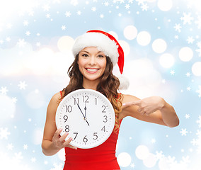 Image showing woman in santa helper hat with clock showing 12