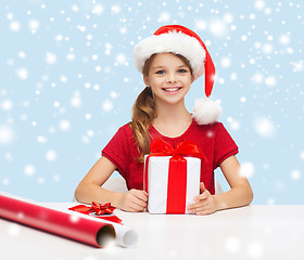 Image showing smiling girl in santa helper hat with gift box