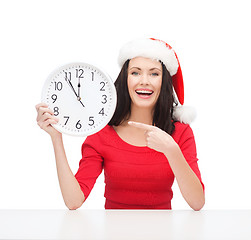 Image showing woman in santa helper hat with clock showing 12