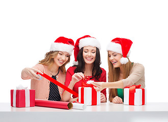 Image showing smiling women in santa helper hats with gift boxes