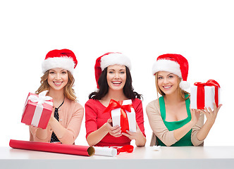Image showing smiling women in santa helper hats with gift boxes