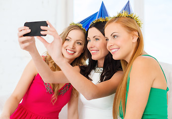 Image showing three smiling women in hats having fun with camera