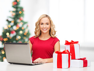 Image showing woman with gift boxes and laptop computer