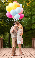 Image showing couple with colorful balloons kissing in the park