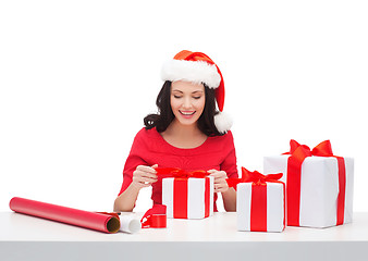 Image showing woman in santa helper hat with many gift boxes