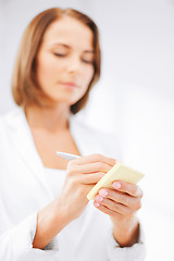 Image showing businesswoman writing on sticky note