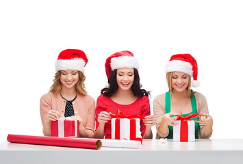 Image showing smiling women in santa helper hats with gift boxes