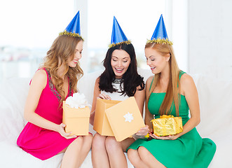 Image showing three smiling women in blue hats with gift boxes