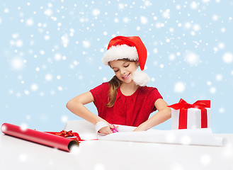 Image showing smiling girl in santa helper hat with gift box