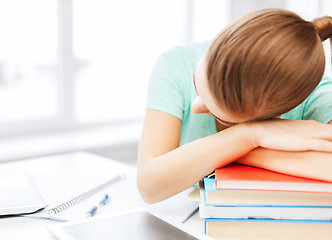 Image showing tired student sleeping on stock of books