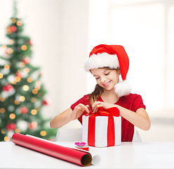 Image showing smiling girl in santa helper hat with gift box