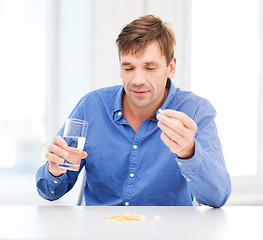 Image showing ill man taking his pills at home