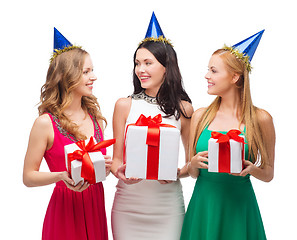 Image showing three smiling women in blue hats with gift boxes