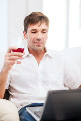 Image showing man with laptop computer and glass of rose wine