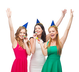 Image showing three smiling women in hats blowing favor horns