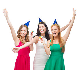 Image showing three smiling women in hats blowing favor horns