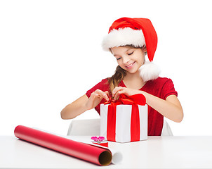 Image showing smiling girl in santa helper hat with gift box