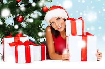 Image showing smiling woman in santa helper hat with gift boxes