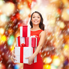 Image showing smiling woman in red dress with many gift boxes