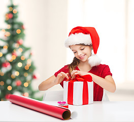 Image showing smiling girl in santa helper hat with gift box