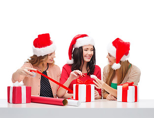 Image showing smiling women in santa helper hats with gift boxes