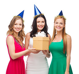 Image showing three smiling women in blue hats with gift box